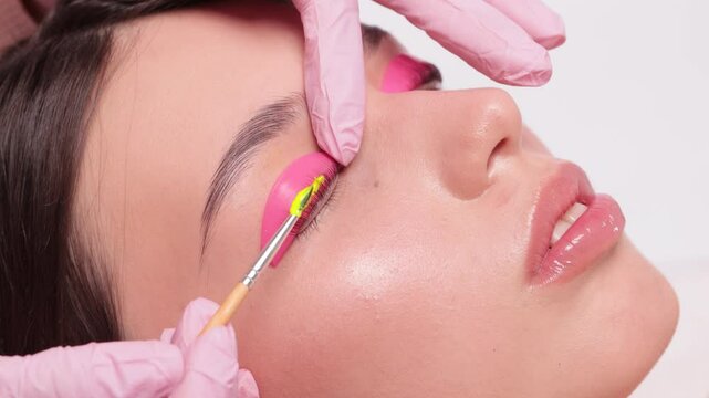 Make-up artist makes the procedure of lamination and dyeing of eyelashes to a beautiful woman in a beauty salon. Eyelash extensions. Eyelashes close-up