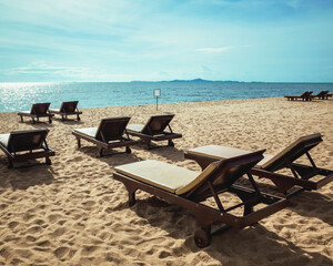 Sun loungers on the tropical beach. Outdoor chairs for relaxation. Seascape with island view. Summer vacation.