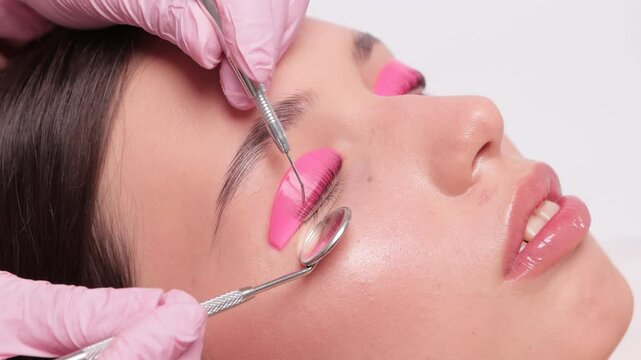 Make-up artist makes the procedure of lamination and dyeing of eyelashes to a beautiful woman in a beauty salon. Eyelash extensions. Eyelashes close-up