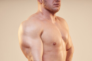 Fototapeta premium Cropped shot of strong mans body topless using arm muscles. Unrecognizable pumped bodybuilder showing triceps and chest musculature isolated on neutral background, copy space