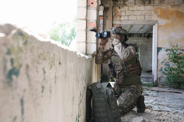 Fototapeta premium Military mission. Soldier in uniform with binoculars inside abandoned building, space for text