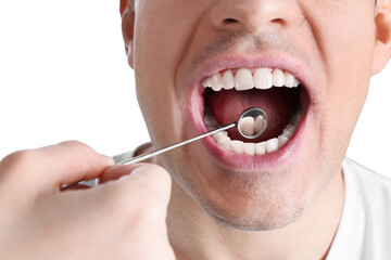 Dentist examining man's teeth and gums with mirror on white background, closeup
