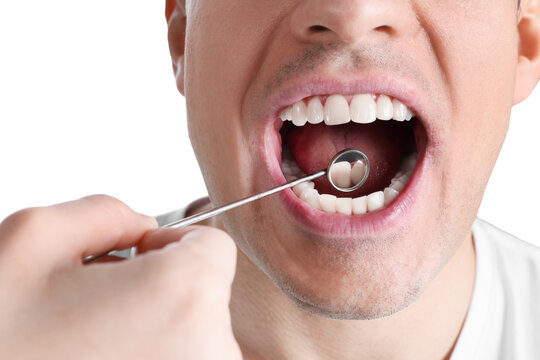 Dentist examining man's teeth and gums with mirror on white background, closeup