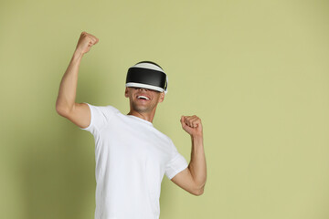 Smiling man using virtual reality headset on light green background