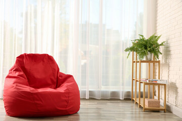 Red bean bag chair on floor in room. Space for text