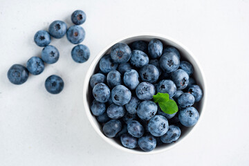 A beautiful display of blueberries adorned with a mint leaf, set against a clean white backdrop