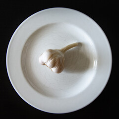 garlic in a white bowl. Garlic lies on a white plate. Healthy eating