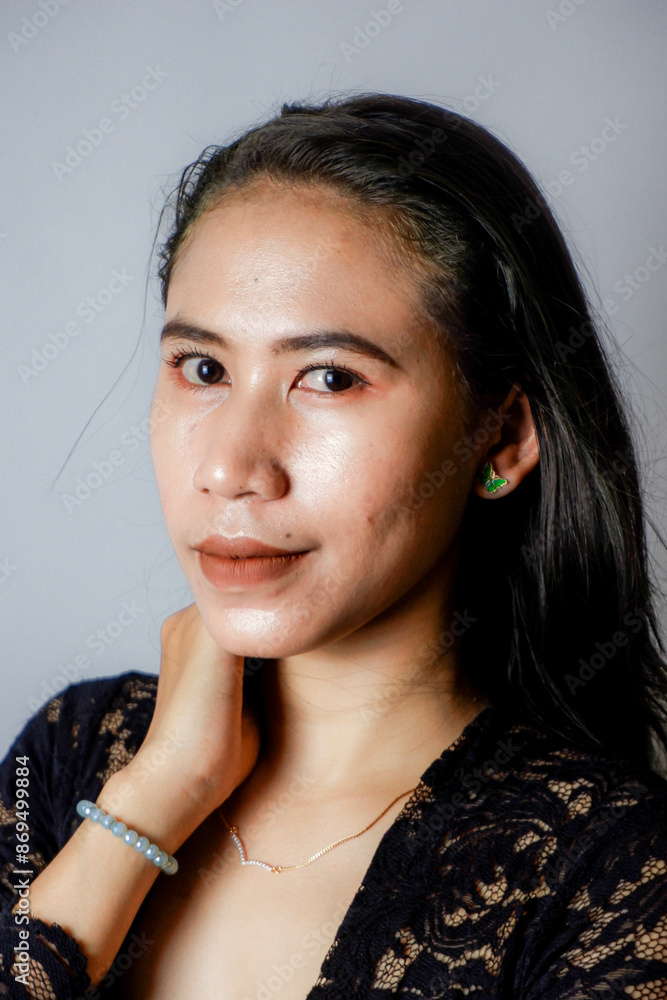 Wall mural portrait of an indonesian woman wearing a black kebaya in the studio with a disheveled pose isolated