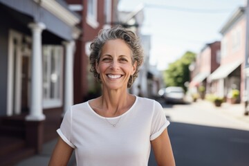 Portrait of a happy woman in her 50s wearing a breathable golf polo isolated on charming small town main street