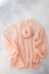 Home hobby, knitting a spider web sweater from pink threads, top view of the sweater and threads