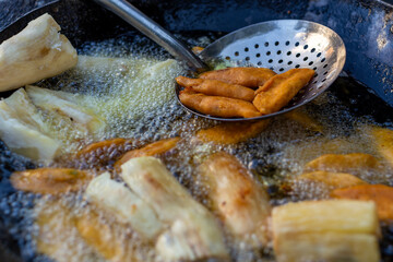 Salvadoran empanadas and yuca or cassava fritters deep frying in bubbling oil. Delicious and...