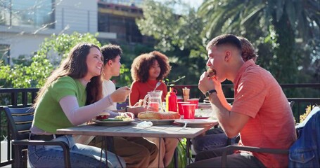 Food, eating and friends with hamburgers for outdoor lunch, event or gathering together on balcony. Party, terrace and group of young people enjoying meal in nature for bonding by wooden table.
