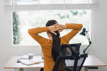 Woman taking a break and stretching at desk in home office.