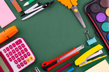 School office supplies stationery on a green background desk with copy space. Back to school concept.