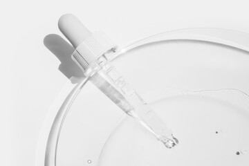 Cosmetic pipette from which liquid is poured into a Petri dish or medical glass on a light...