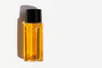 Cosmetic jar with yellow liquid on light background