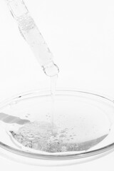 Cosmetic liquid drips from a pipette onto medical glass