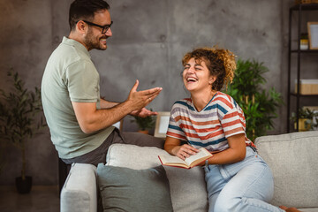 girlfriend sit on sofa read book and discuss whit her boyfriend