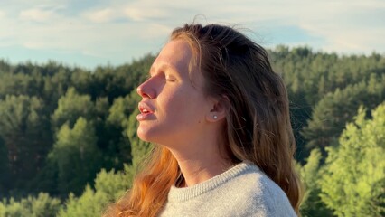 young relaxed woman breathing deep fresh air in the forest