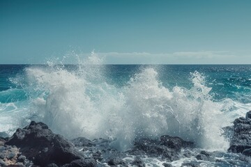 Naklejka premium Ocean spray mist rises from waves crashing against rocks, with a minimal, simple background of a clear, blue horizon.