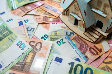 toy house with a roof on euro banknotes as background