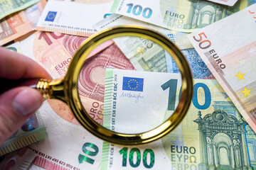 magnifying glass on different euro bills as background. Finance concept