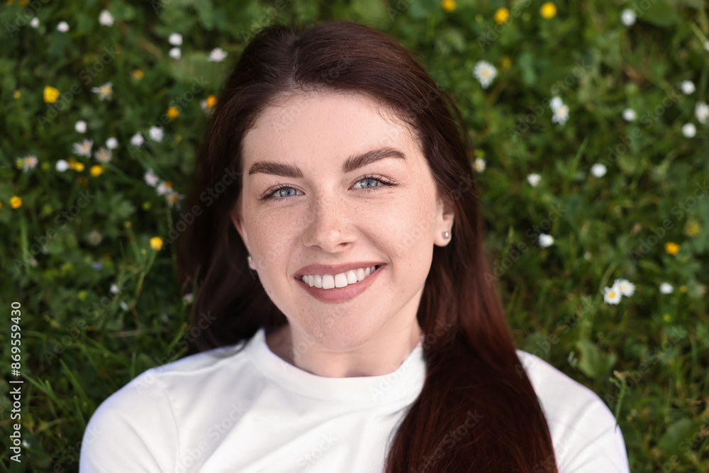 Poster Portrait of smiling woman lying on grass and flowers, top view. Spring vibes