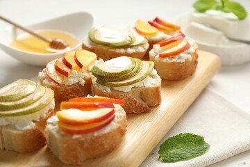 Delicious ricotta bruschettas with pears and apricots on white table, closeup