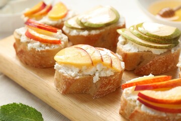 Delicious ricotta bruschettas with pears and apricots on white table, closeup