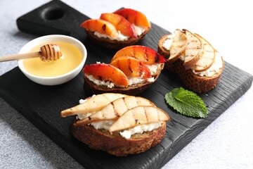 Delicious bruschettas with ricotta cheese and honey on light grey table, closeup
