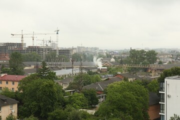 Obraz premium Picturesque view of city with buildings and construction cranes on cloudy day