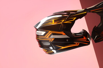 Modern motorcycle helmet with visor on mirror surface against pink background. Space for text