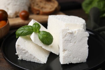 Fresh ricotta (cream cheese) and basil on table, closeup