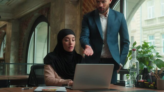 Arabian man boss leader mentor displeased male businessman talk angry with female worker bad result fail problem business documents frustrated muslim woman in hijab employee sad at office desk stress