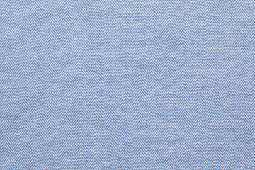 A close-up shot of light blue herringbone jeans fabric, showcasing its unique woven pattern.