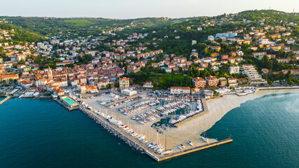 Obraz premium An aerial sunset view of the charming town of Muggia in Friuli Venezia Giulia, Italy with white mucilaginous blooms blanket. This picturesque town, located near the border with Slovenia 