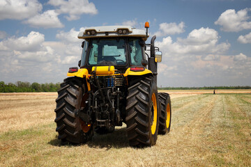 Rear view of a large tractor and farmer work  in a field.