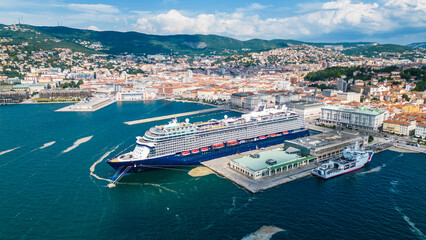 An impressive aerial shot of Trieste, Italy, featuring a majestic cruise ship docked at the port....