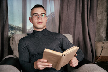 Young attractive man reading a book at home. Handsome guy.