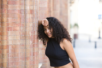 beautiful latin woman with black eyes and dark, long curly hair rests her head on an arm leaning...