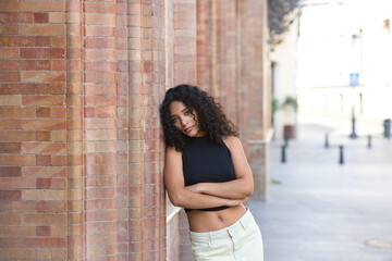 beautiful Latin woman with black eyes and brunette with long curly hair leaning on her side with...