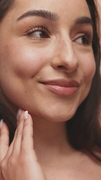 A detailed close-up capturing a woman touching her flawless skin, embodying a natural beauty concept.