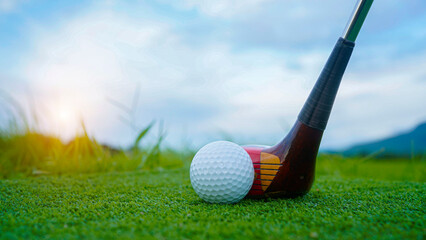 Golf ball and wooden driver on green grass background.