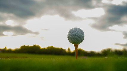 golf ball on tee in beautiful golf course with sunset. Golf ball close up in golf coures.