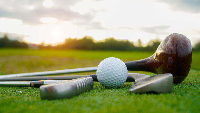 Golf ball and wooden driver on green grass background.