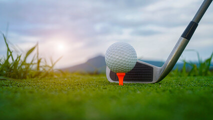Golf ball and wooden driver on green grass background.