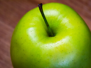 Fresh, juicy green apple presented on wood, ideal for health-related advertising.