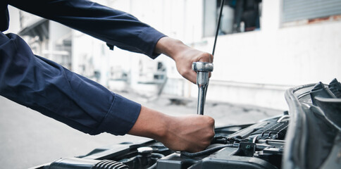 Mechanic using wrench while working on car engine outside the service center , Repair and service.