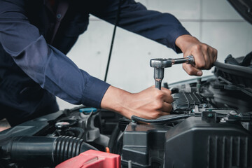 Mechanic using wrench while working on car engine outside the service center , Repair and service.