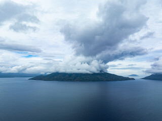 Obraz premium Clouds gather over the volcanic island of Pulau Pura in the middle of Pantar Strait near Alor, Indonesia. This area is part of the Coral Triangle and is home to spectacularly diverse coral reefs.